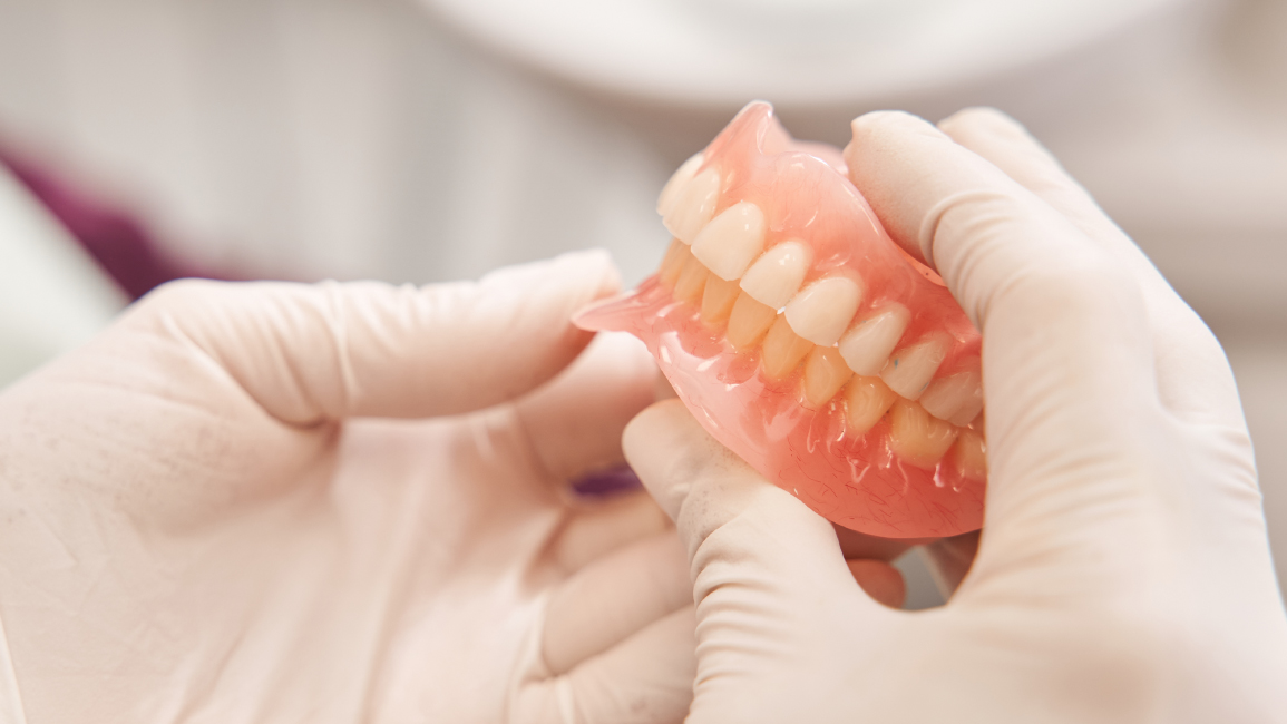 A dentist holding dentures at Nakornthon Hospital Dental Center