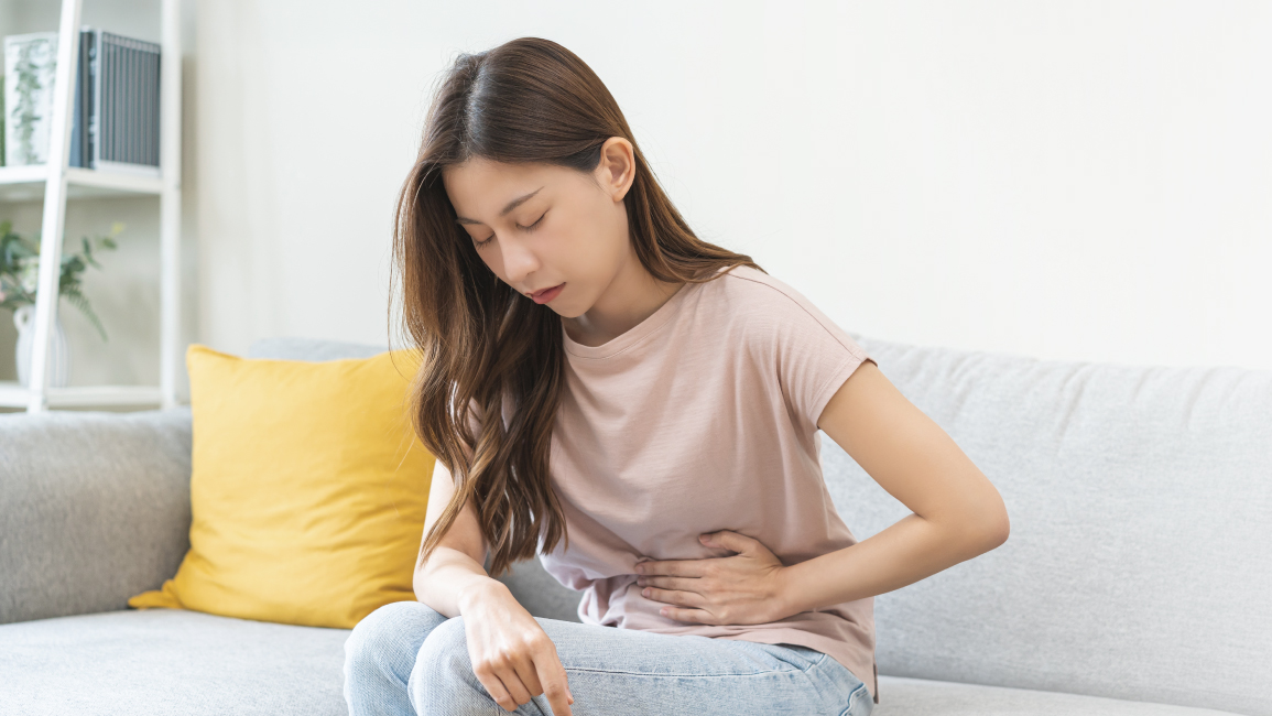 A young woman feels pain in her abdomen. If the stool is also dark, it may be signs of colon cancer.