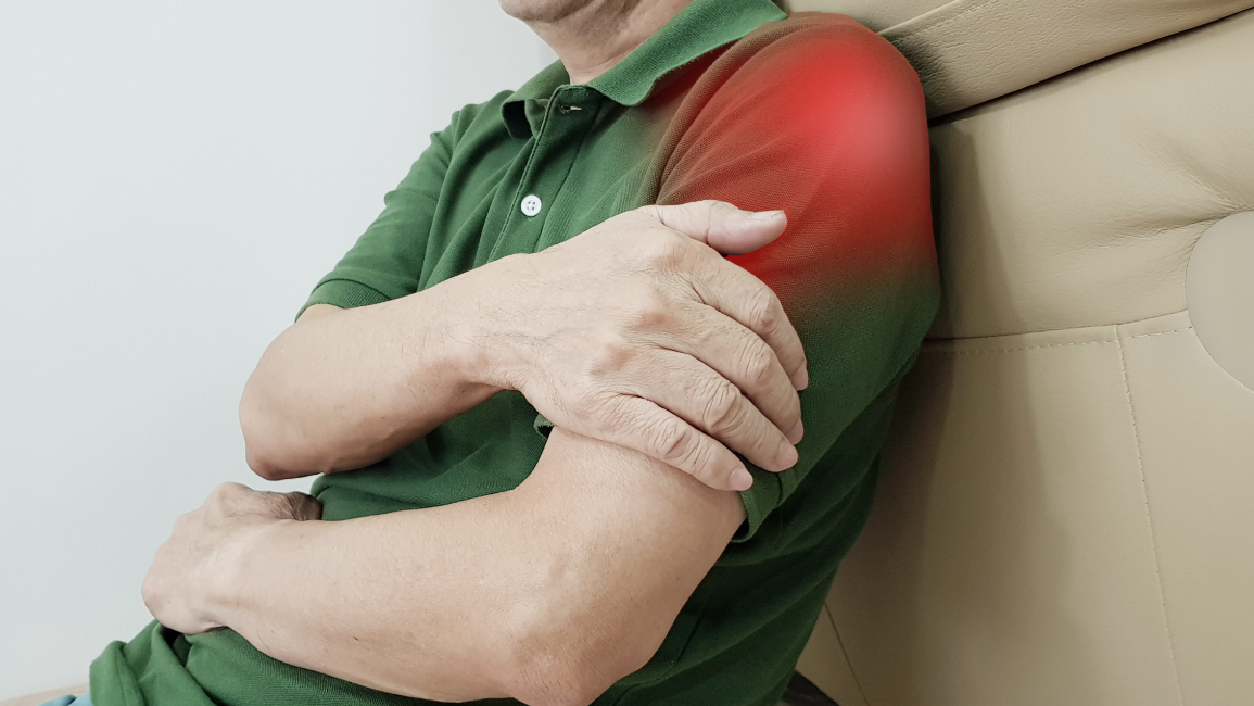 Man holding his shoulder in discomfort, a common sign that may lead to rotator cuff surgery